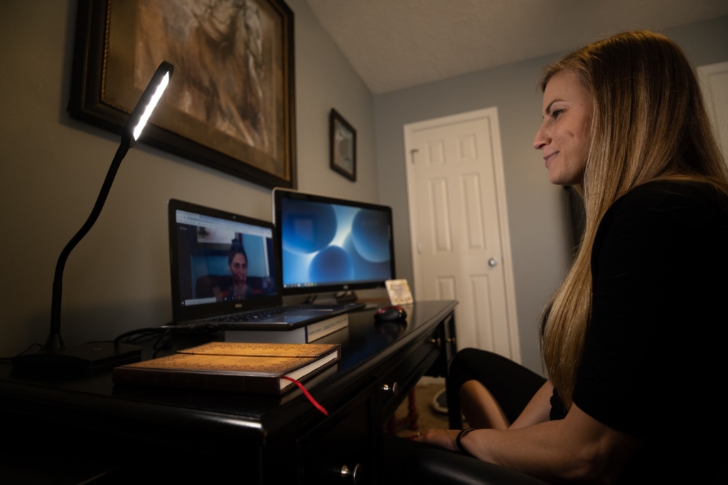 woman sitting at a desk with a client on a therapy virtual meeting