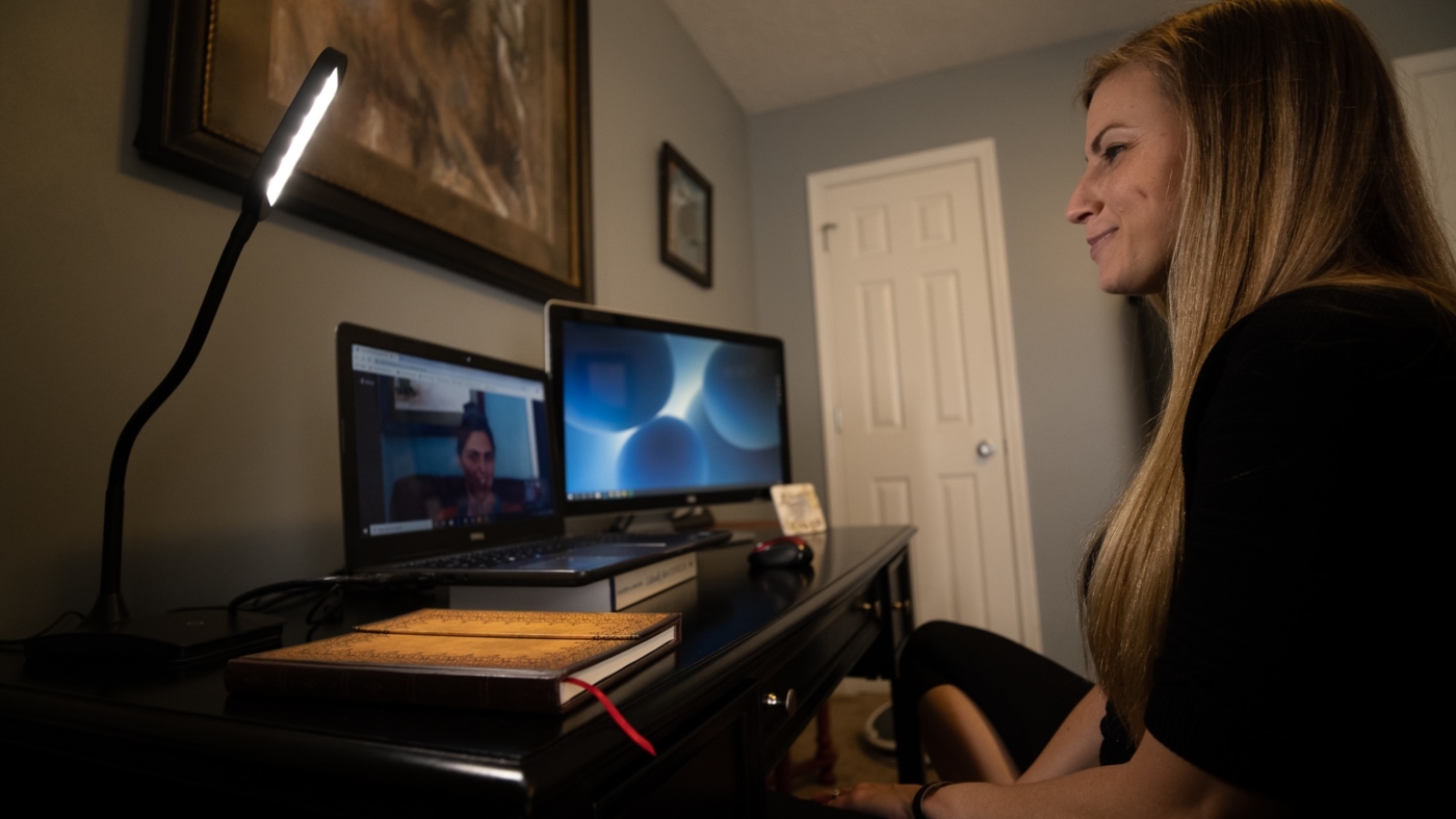 woman sitting at a desk with a client on a therapy virtual meeting