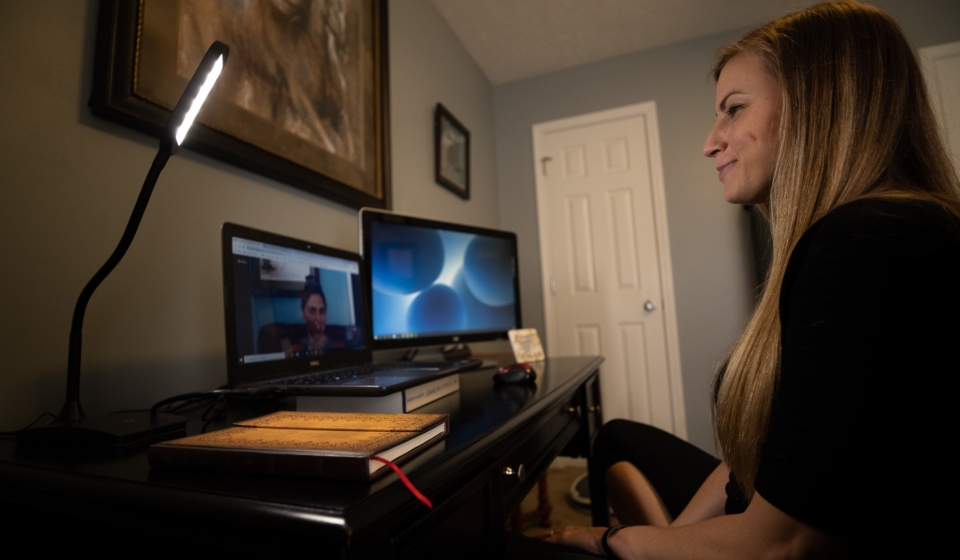 woman sitting at a desk with a client on a therapy virtual meeting